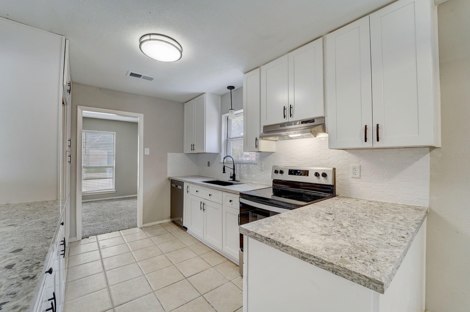 Attainable Greater Houston kitchen update with white cabinets, tile backsplash, and stone-look counters