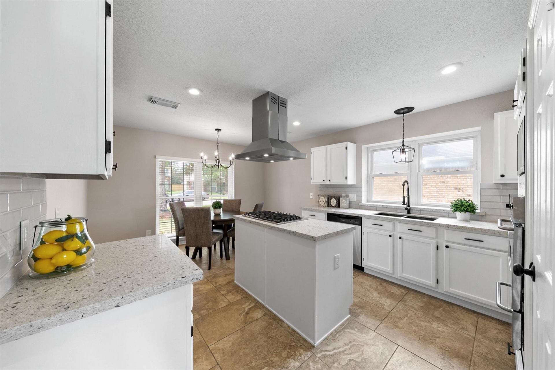 Completed Greater Houston white kitchen renovation with central island, dining area, and statement range hood