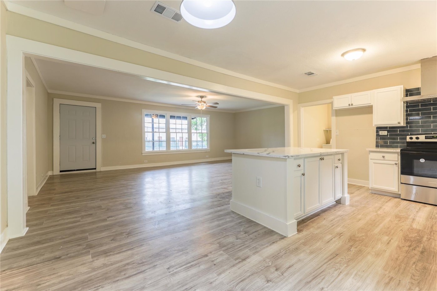 Completed open-concept kitchen and living area with a white island and refreshed flooring