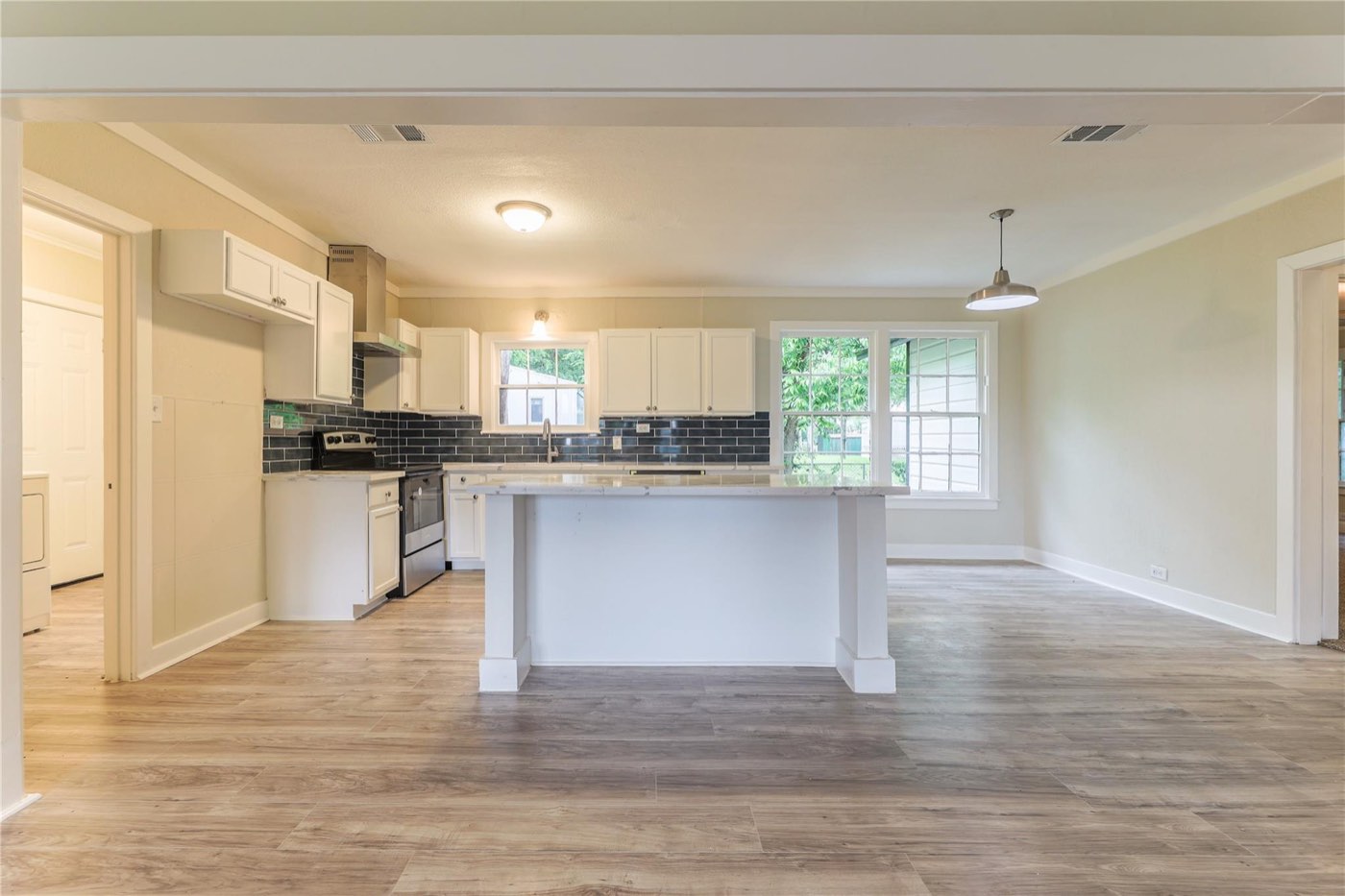 Completed white kitchen with dark subway-tile backsplash and open dining area
