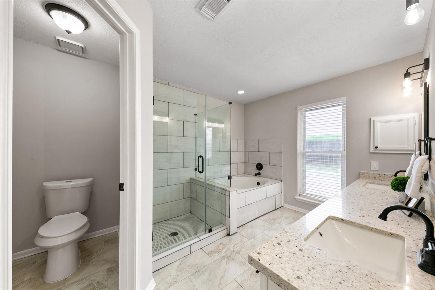 Primary bathroom with glass shower, soaking tub, stone counters, and black fixtures