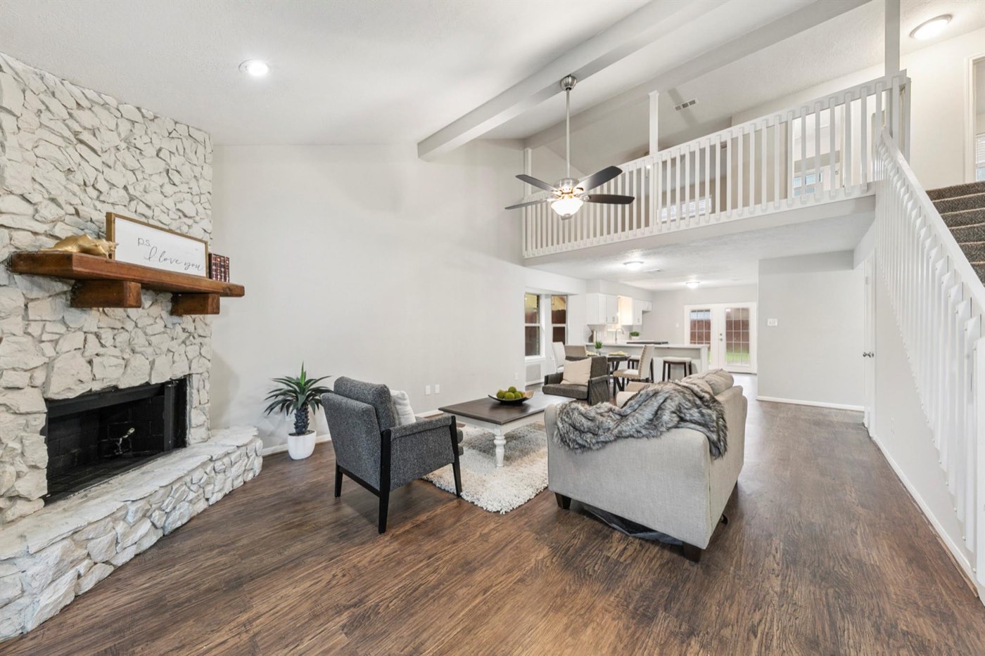 Updated open living room with stone fireplace and bright neutral finishes