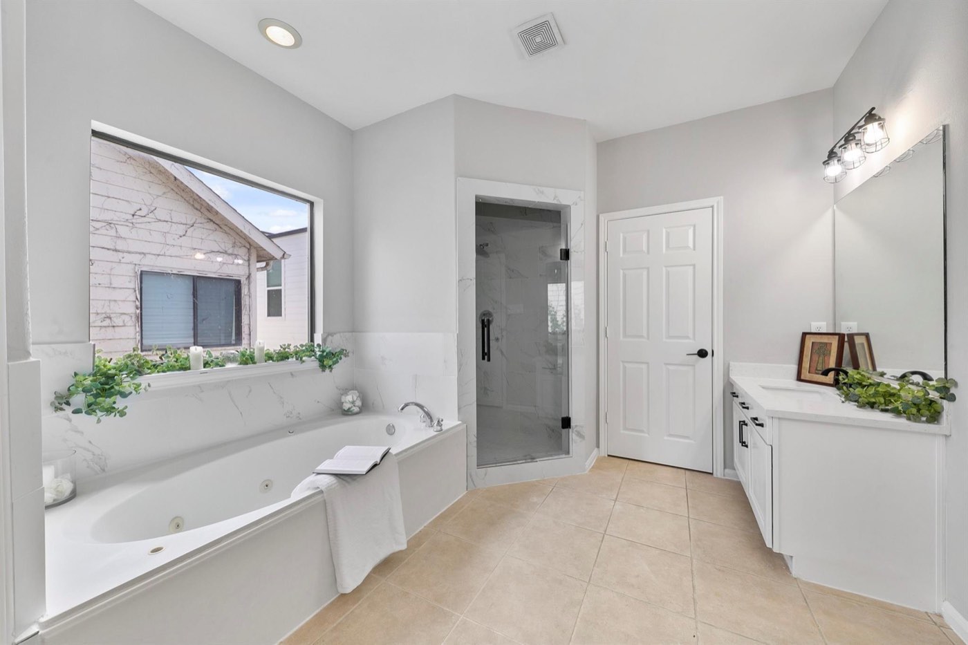 Completed primary bathroom with glass shower, soaking tub, and white cabinetry