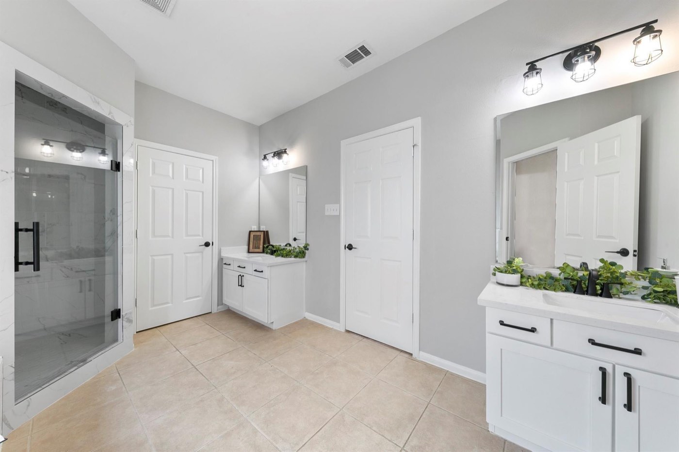 Primary bathroom renovation with black hardware, updated lighting, and glass shower