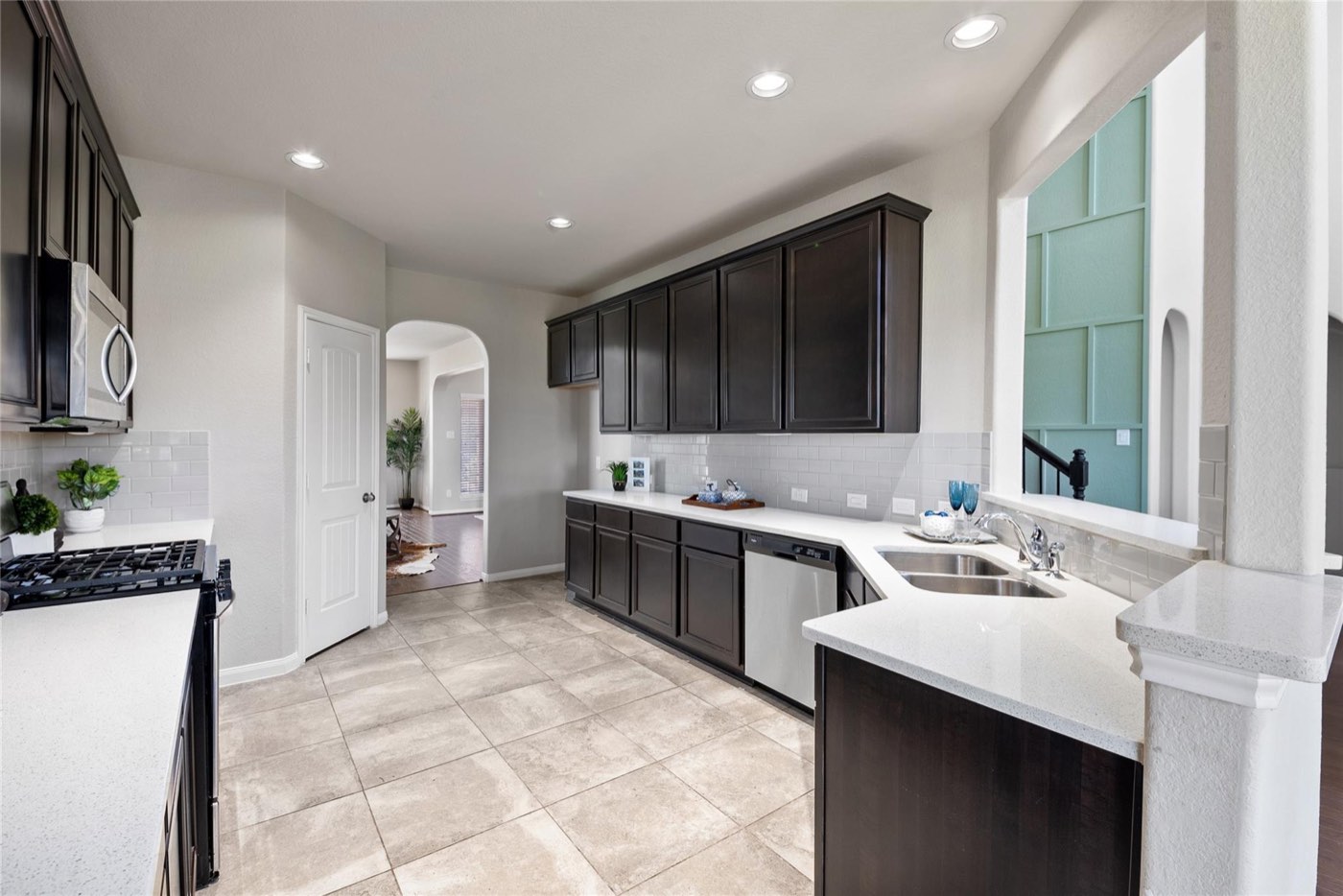Completed kitchen with dark cabinets, white counters, stainless appliances, and open sightlines