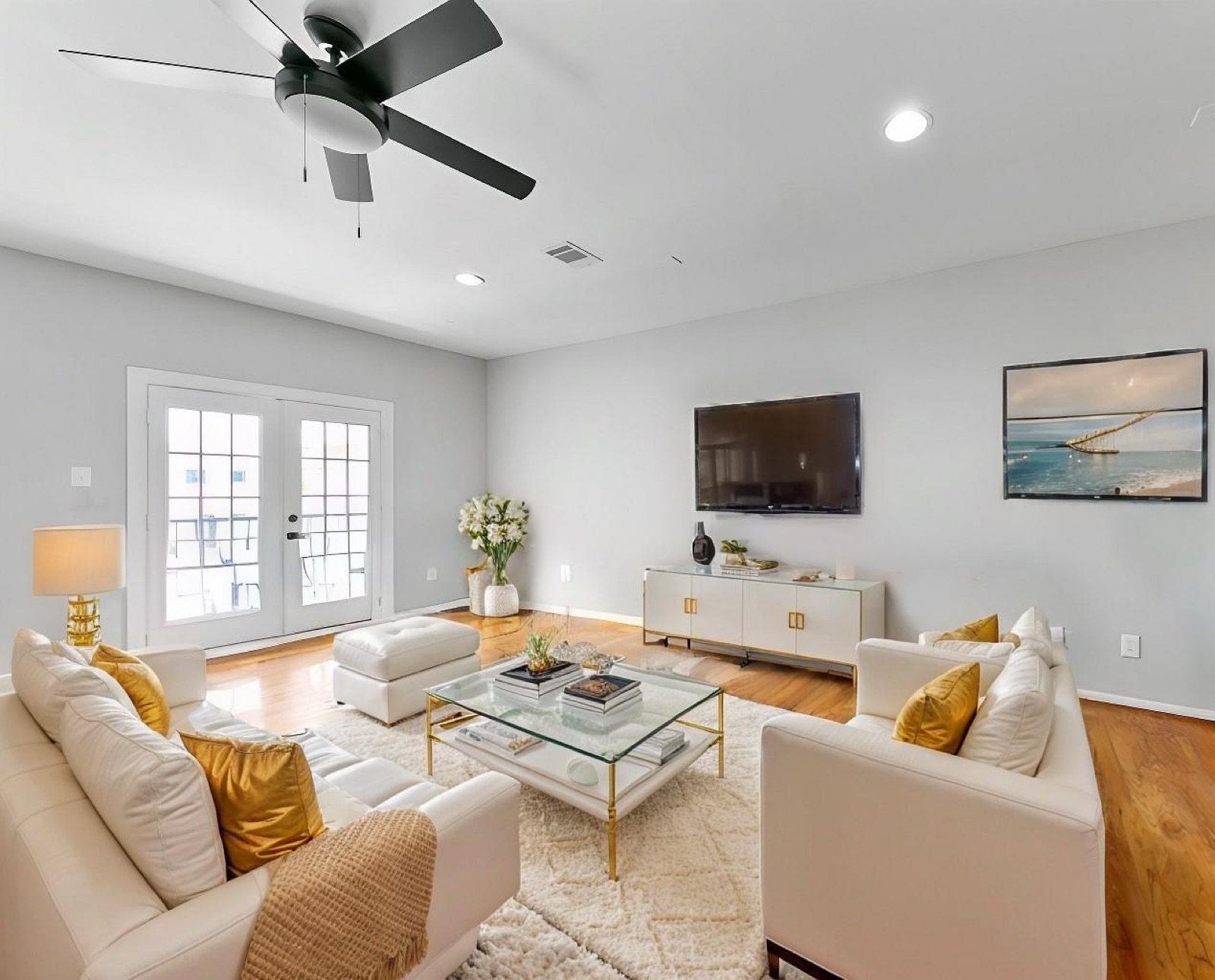 Completed living room with warm wood flooring, recessed lighting, and bright neutral finishes