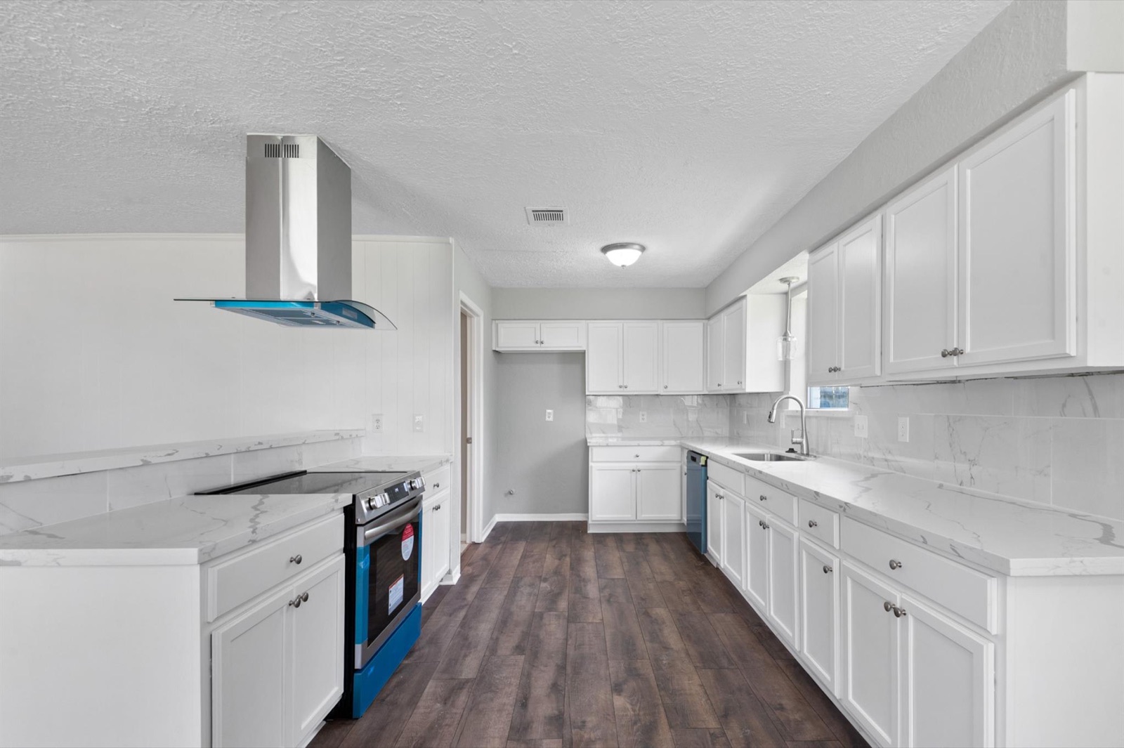 Alternate view of bright kitchen renovation with updated cabinets, counters, flooring, and appliances